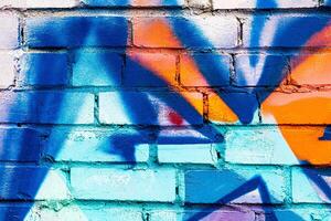 A fragment of colorful graffiti painted on a brick wall. Abstract backdrop for design. photo