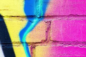A fragment of colorful graffiti painted on a brick wall. Abstract backdrop for design. photo