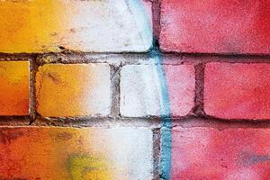A fragment of colorful graffiti painted on a brick wall. Abstract backdrop for design. photo