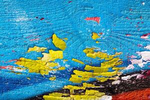 A fragment of colorful graffiti painted on a wooden board with peeling paint close-up. Abstract backdrop for design. photo
