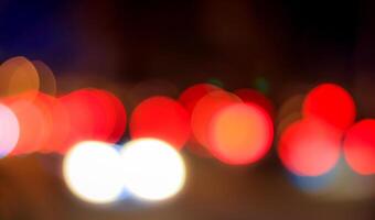 Blurred lights of headlights of cars and lanterns in the night city. Abstract bokeh. photo