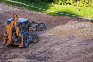 Russia, Kaluga - OCTOBER 27, 2020 A tractor with a bucket leveling a plot of land for construction. photo
