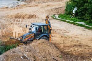 Russia, Kaluga - OCTOBER 27, 2020 A tractor with a bucket leveling a plot of land for construction. photo