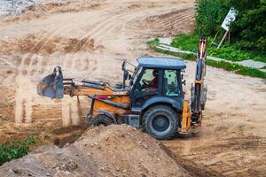 Russia, Kaluga - OCTOBER 27, 2020 A tractor with a bucket leveling a plot of land for construction. photo