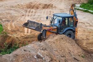 Russia, Kaluga - OCTOBER 27, 2020 A tractor with a bucket leveling a plot of land for construction. photo