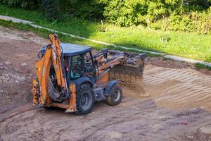 Russia, Kaluga - OCTOBER 27, 2020 A tractor with a bucket leveling a plot of land for construction. photo