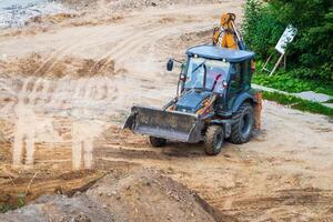 Russia, Kaluga - OCTOBER 27, 2020 A tractor with a bucket leveling a plot of land for construction. photo