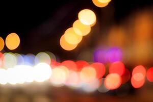 Blurred lights of headlights of cars and lanterns in the night city. Abstract bokeh. photo