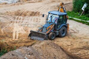 Russia, Kaluga - OCTOBER 27, 2020 A tractor with a bucket leveling a plot of land for construction. photo