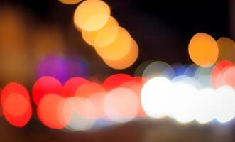 Blurred lights of headlights of cars and lanterns in the night city. Abstract bokeh. photo