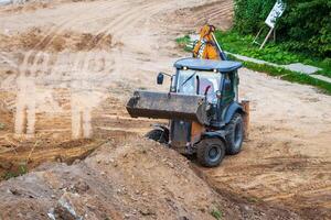 Russia, Kaluga - OCTOBER 27, 2020 A tractor with a bucket leveling a plot of land for construction. photo
