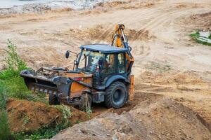 Russia, Kaluga - OCTOBER 27, 2020 A tractor with a bucket leveling a plot of land for construction. photo