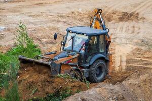 Russia, Kaluga - OCTOBER 27, 2020 A tractor with a bucket leveling a plot of land for construction. photo