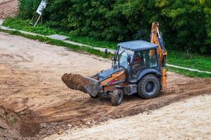 Russia, Kaluga - OCTOBER 27, 2020 A tractor with a bucket leveling a plot of land for construction. photo