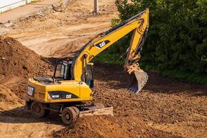 Russia, Kaluga - OCTOBER 27, 2020 A tractor with a bucket leveling a plot of land for construction. photo