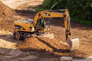 Russia, Kaluga - OCTOBER 27, 2020 A tractor with a bucket leveling a plot of land for construction. photo