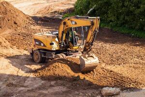 Russia, Kaluga - OCTOBER 27, 2020 A tractor with a bucket leveling a plot of land for construction. photo