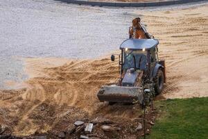 Russia, Kaluga - OCTOBER 27, 2020 Tractor breaking the old asphalt with a bucket before the construction. photo