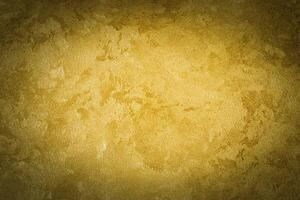 Golden decorative plaster texture with vignette. Abstract grunge background with copy space. photo