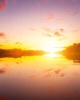 A sunset or sunrise scene over a lake or river with dramatic cloudy skies reflecting in the water on a summer evening or morning. photo