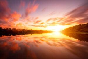 A sunset or sunrise scene over a lake or river with dramatic cloudy skies reflecting in the water on a summer evening or morning. photo