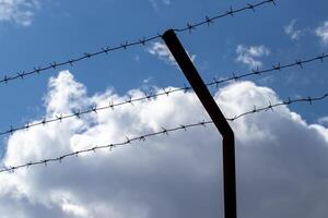 Barbed wire on the background of the cloudy sky. The concept of border closure, prison or loss of freedom. photo