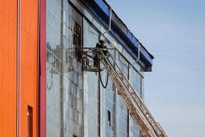 Russia, Kaluga - SEPTEMBER 08, 2020 A team of firefighters in protective suits and helmets on the stairs extinguishing a fire in a building with a broken window. photo