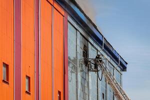 Russia, Kaluga - SEPTEMBER 08, 2020 A team of firefighters in protective suits and helmets on the stairs extinguishing a fire in a building with a broken window. photo
