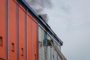 Russia, Kaluga - SEPTEMBER 08, 2020 A team of firefighters in protective suits and helmets on the stairs extinguishing a fire in a building with a broken window. photo