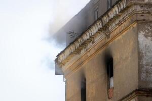 Black smoke rising from a burning building with a cloudy sky. photo