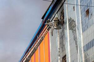 Russia, Kaluga - SEPTEMBER 08, 2020 A team of firefighters in protective suits and helmets on the stairs extinguishing a fire in a building with a broken window. photo
