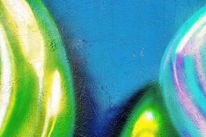 A fragment of colorful graffiti painted on a wall. Abstract urban background. photo