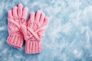 Pink knitted gloves on a snowy winter background, top view, providing warm finger protection. photo