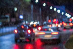 Blurry lights of moving cars and lanterns reflecting on the wet asphalt in the night city in rain. photo