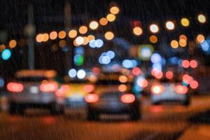 Blurry lights of moving cars and lanterns reflecting on the wet asphalt in the night city in rain. photo