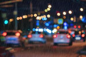 Blurry lights of moving cars and lanterns reflecting on the wet asphalt in the night city in rain. photo