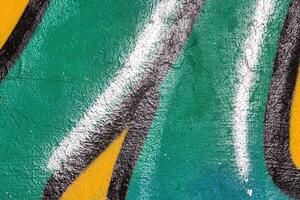 A fragment of colorful graffiti painted on a wall. Abstract urban background. photo