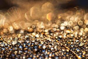 Dew drops on an autumn fallen leaf, shimmering in the sun, shot in close-up with bokeh. Abstract macro background. photo