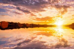 Sunset on the river at summer evening with clouds and trees. Water reflection of a sky. photo