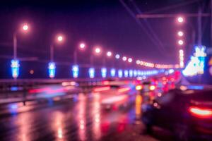Blurry lights of moving cars and lanterns reflecting on the wet asphalt in the night city. photo