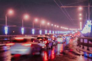 Blurry lights of moving cars and lanterns reflecting on the wet asphalt in the night city. photo