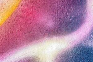 A fragment of colorful graffiti painted on a wall. Abstract urban background. photo
