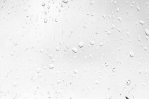 Rain drops on window glasses surface with gray sky background. Natural backdrop of raindrops. The concept of bad rainy weather. photo