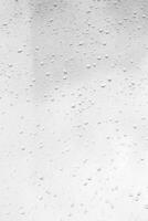 Rain drops on window glasses surface with gray sky background. Natural backdrop of raindrops. The concept of bad rainy weather. photo