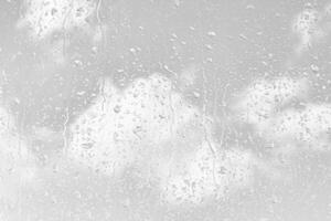 Rain drops on window glasses surface with gray sky background. Natural backdrop of raindrops. The concept of bad rainy weather. photo