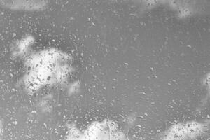 Rain drops on window glasses surface with gray sky background. Natural backdrop of raindrops. The concept of bad rainy weather. photo