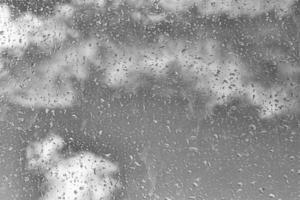 Rain drops on window glasses surface with gray sky background. Natural backdrop of raindrops. The concept of bad rainy weather. photo