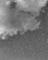 Rain drops on window glasses surface with gray sky background. Natural backdrop of raindrops. The concept of bad rainy weather. photo