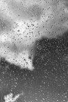 Rain drops on window glasses surface with gray sky background. Natural backdrop of raindrops. The concept of bad rainy weather. photo