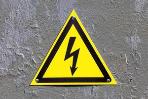 High voltage sign with lightning on a yellow background. photo